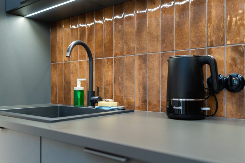 An image of a modern kitchen counter with a sink and a kettle