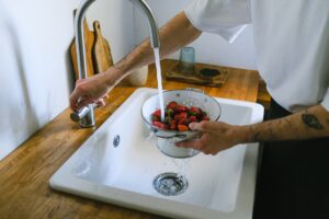 An image of a person washing fruits in a sink
